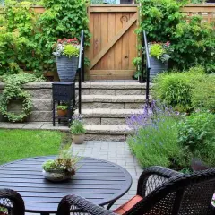 Ein idyllischer, kleiner Garten mit Sitzbereich, Stufen und üppiger Bepflanzung.