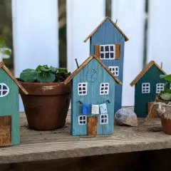 Kleine Holzhäuser, die zum **Holz Gartendeko selber machen** einladen. Bunte Häuschen mit Wäscheleine und Blumentöpfen.