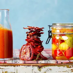Glas mit eingelegten Tomaten, getrocknete Tomaten und eine Flasche Tomatensauce – alles für Tomaten haltbar machen.