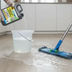 Reinigungsmittel wird in Eimer gegossen, um flecken auf steinfliesen zu entfernen. Ein Mopp liegt bereit.