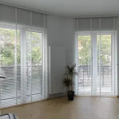 Büro mit vergilbten Plissees reinigen. Helle Räume mit viel Tageslicht, ein Schreibtisch und ein Regal.