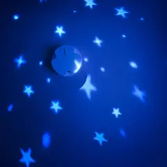 Ein weißer Rauchmelder projiziert Sterne und einen Mond an eine blaue Wand.