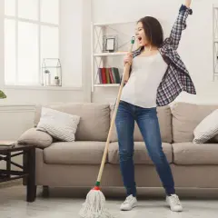 Frau singt und tanzt mit einem Mopp, während sie ihr Linoleum mit Hausmitteln reinigt.