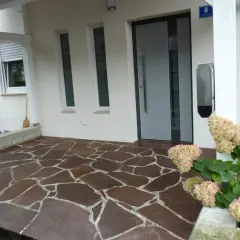 Vor dem Haus liegt ein Boden aus unregelmäßigen Porphyrplatten. Mit Hausmitteln lässt sich dieser Porphyr reinigen und erstrahlt wieder in neuem Glanz.