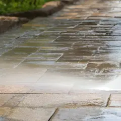 Hochdruckreiniger säubert Terrassensteine. Der Wasserstrahl entfernt Schmutz und lässt die Steine wieder wie neu aussehen.