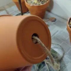 Ein Blumentopf wird zur Vogelfutterstation. Ein Seil wird durch das Loch gezogen, um die Futterstation aufzuhängen.