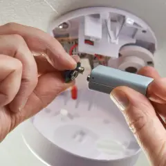 Hände wechseln die Batterie eines Rauchmelders. Der abus rwm120 batterie wechseln ist einfach.