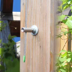 Selbstgebaute Rankhilfe aus Metall: Ein Drahtseil wird an einem Holzpfosten befestigt, um Kletterpflanzen Halt zu geben.