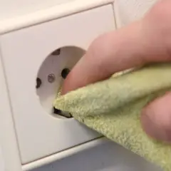 Finger mit Tuch reinigt Steckdose, um sie sicher und sauber zu halten. Steckdosen reinigen ohne abschrauben ist so einfach.