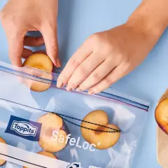 Hände legen halbe Pflaumen in einen Gefrierbeutel. So lassen sich die Früchte perfekt für später einfrieren.