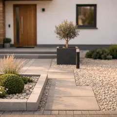 Moderne kleine Vorgarten Ideen: Kieswege, geometrische Beete mit Buchsbaum und Ziergras, ein Olivenbaum im Kubus vor dem Haus.