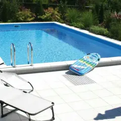 Ein **Holzpool selber bauen ohne Bausatz** ist möglich! Hier ist ein fertiger Pool mit Liegestühlen und aufblasbarem Spielzeug im Garten.