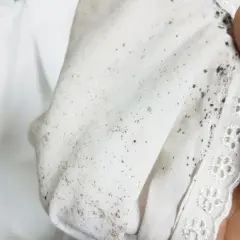 Schimmelige Stoffe: Ein Blick auf hartnäckige stockflecken kleidung entfernen. Die weißen Textilien sind mit dunklen Flecken übersät.