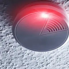 Ein Minol Rauchmelder blinkt rot. Er ist an einer Decke montiert und warnt vor Gefahr.