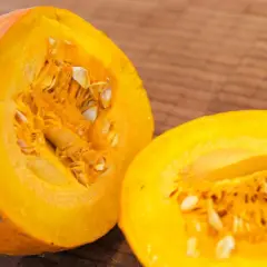 Eine leuchtend orangefarbene Hokkaido-Kürbishälfte liegt neben der anderen, bereit für die Ernte und Zubereitung.
