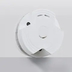 Ein weißer Rauchmelder, der auf einer grauen Fläche schwebt. Er ist so konzipiert, dass er leicht zu bedienen ist, um den Rauchmelder auszuschalten.