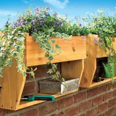 Holz-Blumenkasten selber bauen: Hängende Pflanzen schmücken die Wand. Darunter ein Metallkästchen und eine grüne Gießkanne.