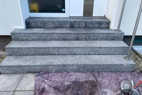Treppenstufen aus Waschbeton werden mit Hausmitteln zum Naturstein versiegeln vorbereitet. Ein Schutzvlies liegt bereit.