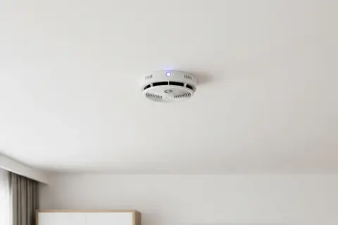 Ein weißer Hekatron Rauchmelder mit blauer LED piept ohne Grund an der Decke.