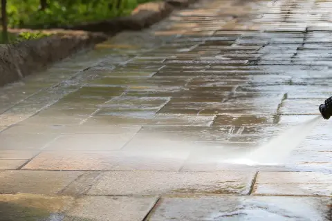 Hochdruckreiniger säubert Terrassensteine. Der Wasserstrahl entfernt Schmutz und lässt die Steine wieder wie neu aussehen.