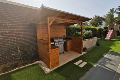 Ein schöner Grillunterstand, den man selber bauen kann, mit Gasgrill, Arbeitsfläche und gemütlicher Beleuchtung.