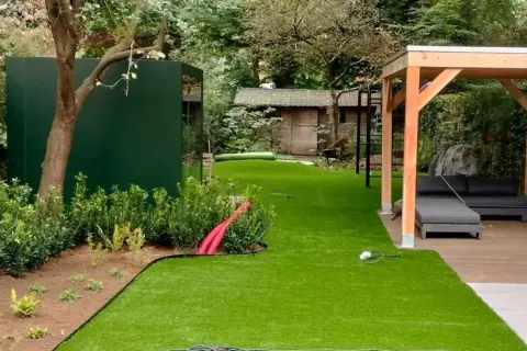 Ein schmal kleinen garten gestalten mit Kunstrasen, Holzpavillon und moderner grüner Wand.
