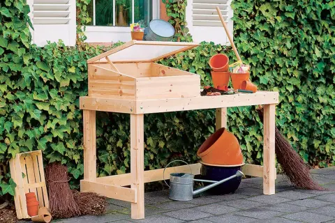 Ein **Pflanztisch selber bauen** ist mit diesem Holztisch leicht gemacht. Er ist mit einem Frühbeetaufsatz und Gartengeräten ausgestattet.