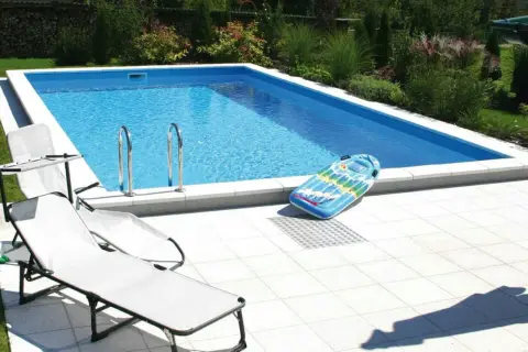 Ein **Holzpool selber bauen ohne Bausatz** ist möglich! Hier ist ein fertiger Pool mit Liegestühlen und aufblasbarem Spielzeug im Garten.