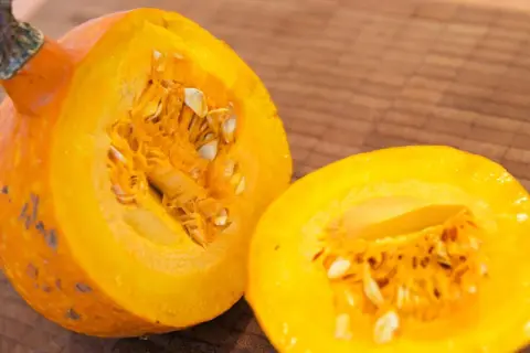 Eine leuchtend orangefarbene Hokkaido-Kürbishälfte liegt neben der anderen, bereit für die Ernte und Zubereitung.