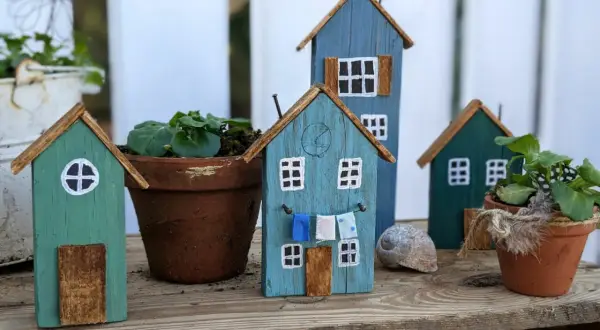 Kleine Holzhäuser, die zum **Holz Gartendeko selber machen** einladen. Bunte Häuschen mit Wäscheleine und Blumentöpfen.