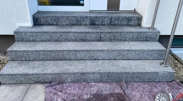 Treppenstufen aus Waschbeton werden mit Hausmitteln zum Naturstein versiegeln vorbereitet. Ein Schutzvlies liegt bereit.