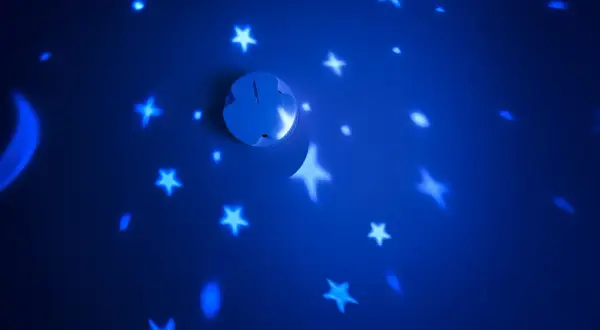 Ein weißer Rauchmelder projiziert Sterne und einen Mond an eine blaue Wand.
