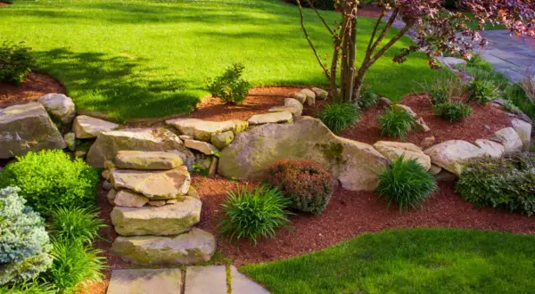 Ein schöner Garten gestalten mit wenig Geld: Steine, Rindenmulch und pflegeleichte Pflanzen schaffen eine natürliche Optik.