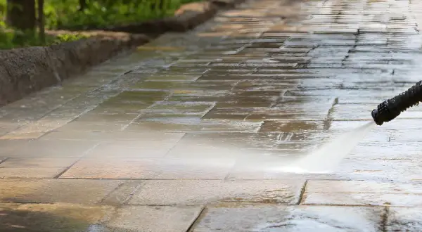 Hochdruckreiniger säubert Terrassensteine. Der Wasserstrahl entfernt Schmutz und lässt die Steine wieder wie neu aussehen.