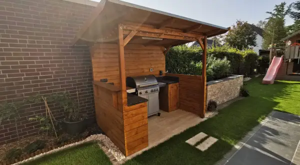 Ein schöner Grillunterstand, den man selber bauen kann, mit Gasgrill, Arbeitsfläche und gemütlicher Beleuchtung.