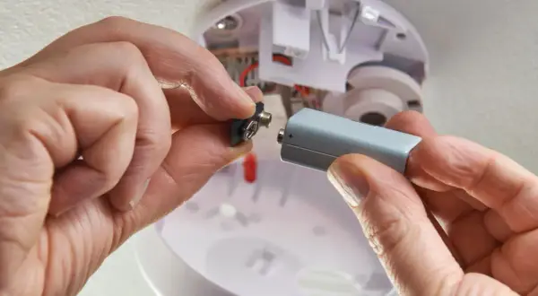 Hände wechseln die Batterie eines Rauchmelders. Der abus rwm120 batterie wechseln ist einfach.
