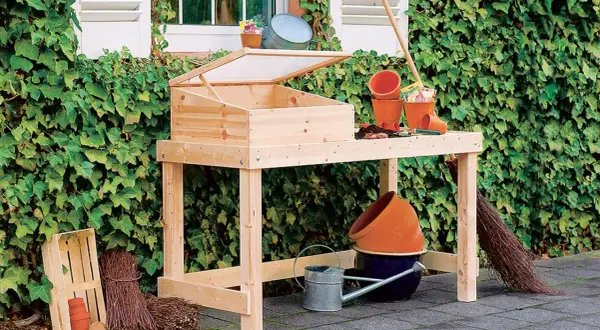 Ein **Pflanztisch selber bauen** ist mit diesem Holztisch leicht gemacht. Er ist mit einem Frühbeetaufsatz und Gartengeräten ausgestattet.