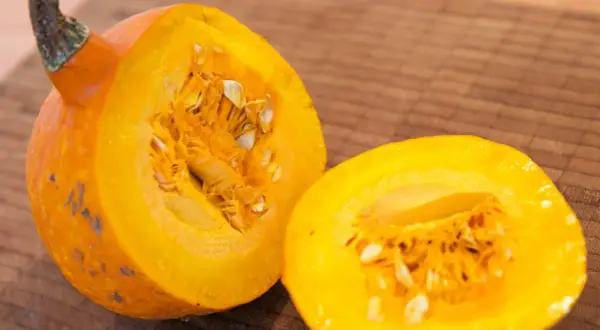 Eine leuchtend orangefarbene Hokkaido-Kürbishälfte liegt neben der anderen, bereit für die Ernte und Zubereitung.