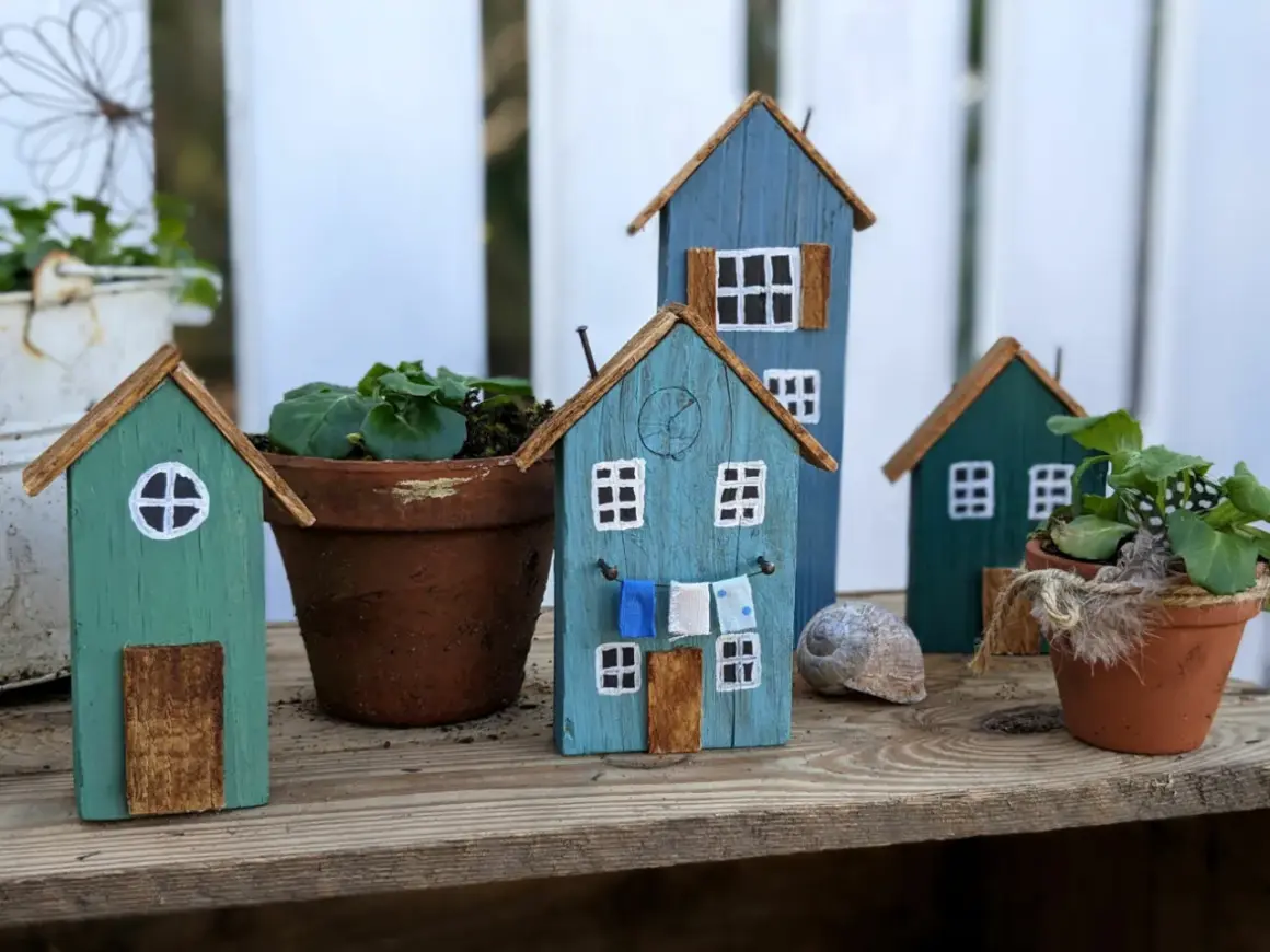Kleine Holzhäuser, die zum **Holz Gartendeko selber machen** einladen. Bunte Häuschen mit Wäscheleine und Blumentöpfen.