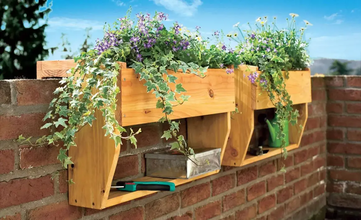 Holz-Blumenkasten selber bauen: Hängende Pflanzen schmücken die Wand. Darunter ein Metallkästchen und eine grüne Gießkanne.