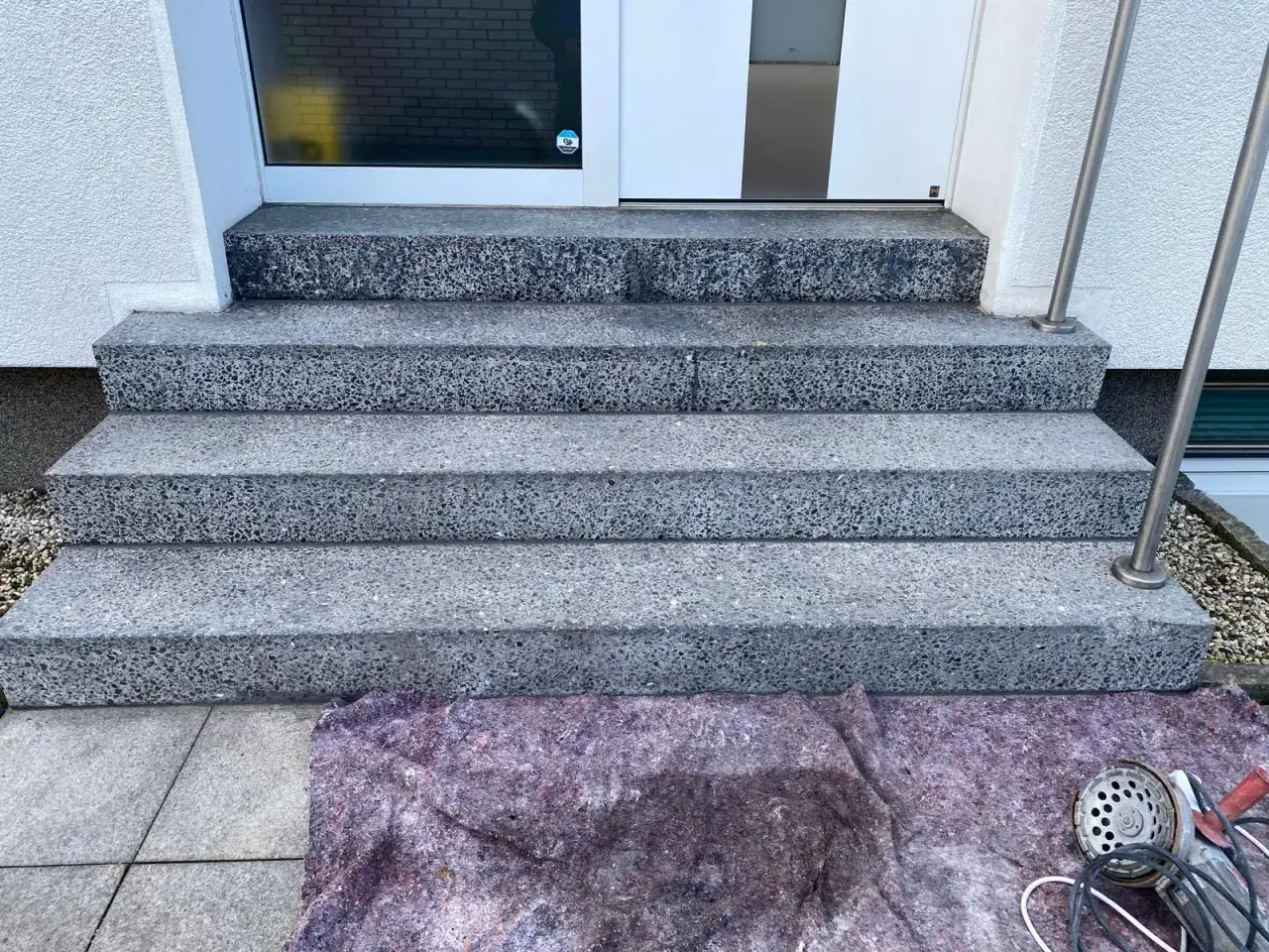 Treppenstufen aus Waschbeton werden mit Hausmitteln zum Naturstein versiegeln vorbereitet. Ein Schutzvlies liegt bereit.