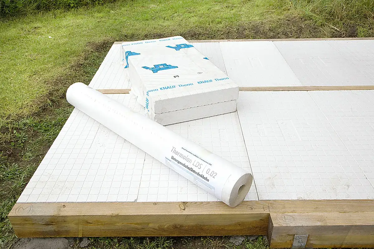 Materialien f&uuml;r das Gartenhaus selber bauen: D&auml;mmplatten und eine Rolle Unterspannbahn liegen bereit auf dem Holzrahmen.
