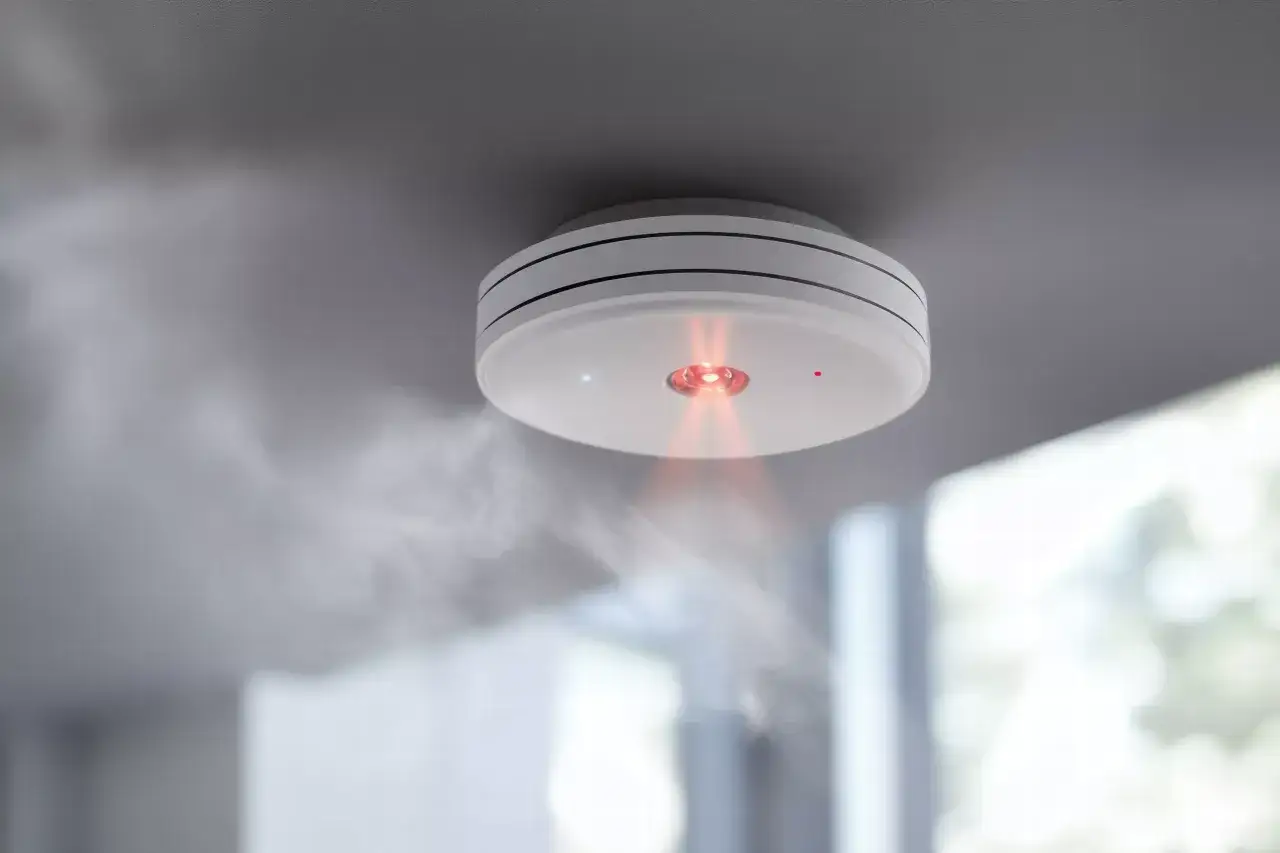 Rauch steigt von einem Rauchmelder auf, der an der Decke montiert ist. Die rote LED leuchtet. Was kostet ein Feuerwehreinsatz bei Fehlalarm?
