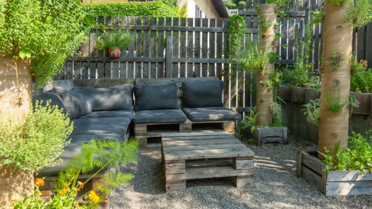 Gem&uuml;tliche Lounge-Ecke mit Palettenm&ouml;beln und vertikalen Pflanzs&auml;ulen. Ein sch&ouml;nes Beispiel, wie man einen Garten gestalten mit wenig Geld kann.