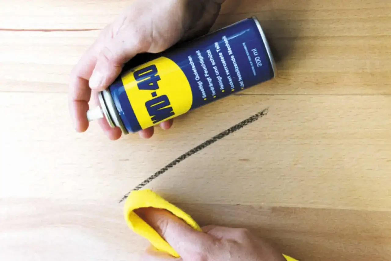 WD-40 Dose hilft, schwarze Streifen auf Linoleum zu entfernen. Ein gelbes Tuch wird zum Abwischen bereitgehalten.