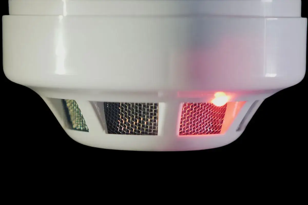 Rauchmelder mit rotem Licht und Gitter. Ein hochfrequentes Piepen in der Wohnung k&ouml;nnte von diesem Ger&auml;t kommen.