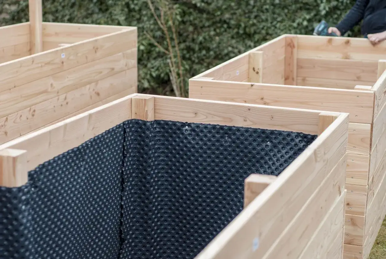 Holzrahmen f&uuml;r ein Hochbeet bauen. Die Innenseiten sind mit Noppenfolie ausgekleidet, um Feuchtigkeit abzuleiten.