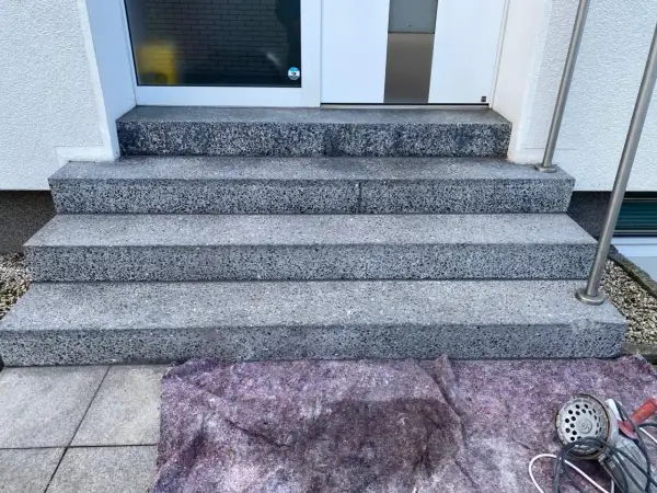 Treppenstufen aus Waschbeton werden mit Hausmitteln zum Naturstein versiegeln vorbereitet. Ein Schutzvlies liegt bereit.