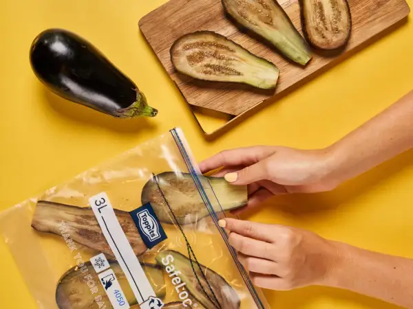 Hände legen Auberginenscheiben zum Aubergine einfrieren in einen Gefrierbeutel.