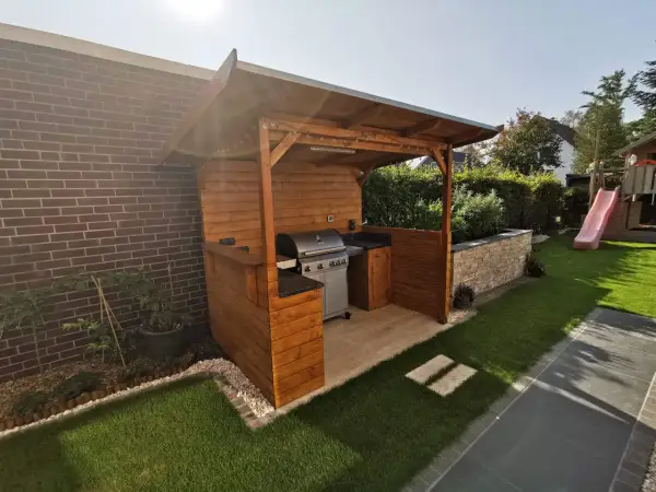 Ein schöner Grillunterstand, den man selber bauen kann, mit Gasgrill, Arbeitsfläche und gemütlicher Beleuchtung.